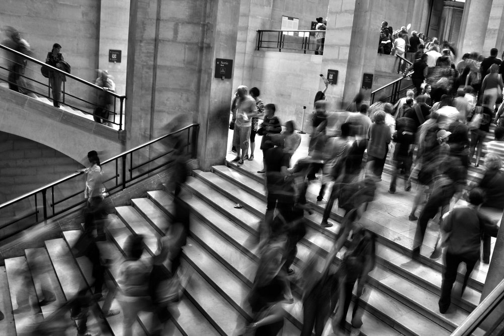 Black and white of busy stairs with people coming and going
