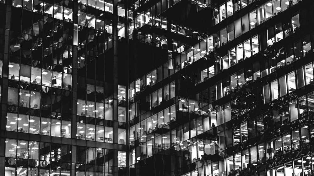 Black and white side of a building with many office blocks and office workers