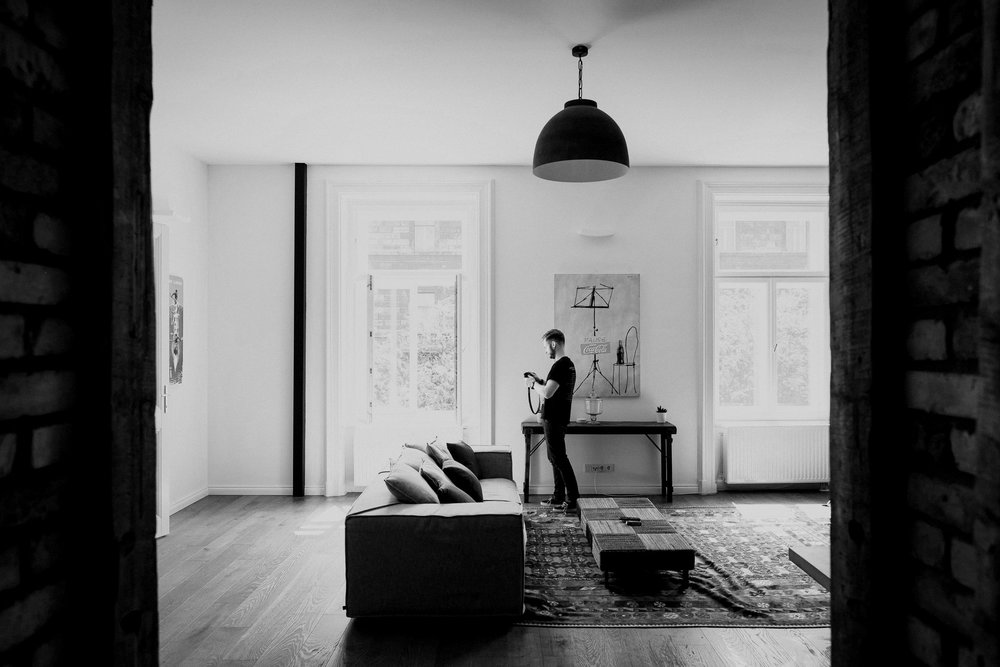 Black and white of man holding camera in smart, large living room