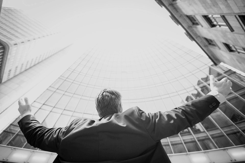 Black and white of business man raising his hands to the sky