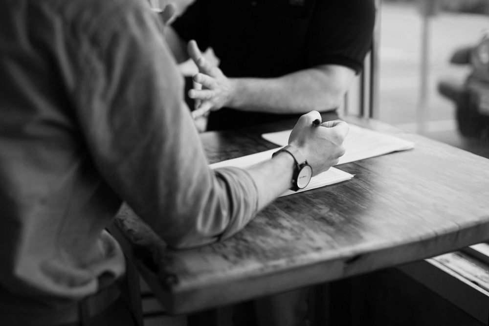 Black and white of a hand with a pen about to write on paper