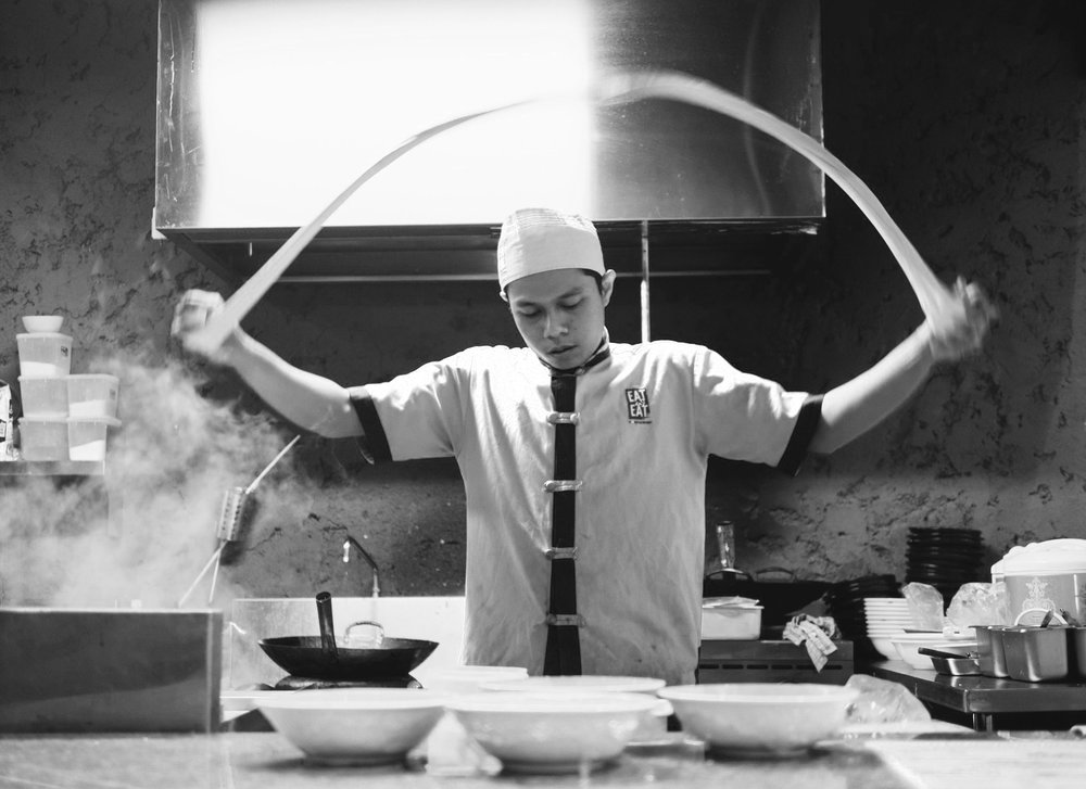 Black and white of a chef skilfully shaping dough