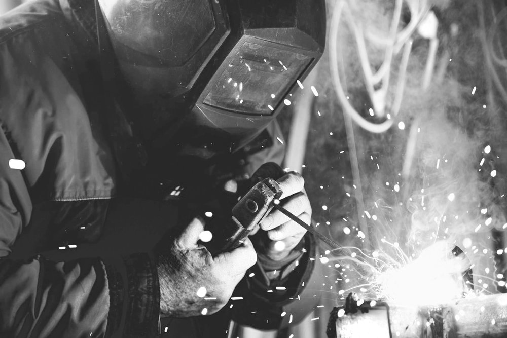 Black and white of a welder welding metal with sparks