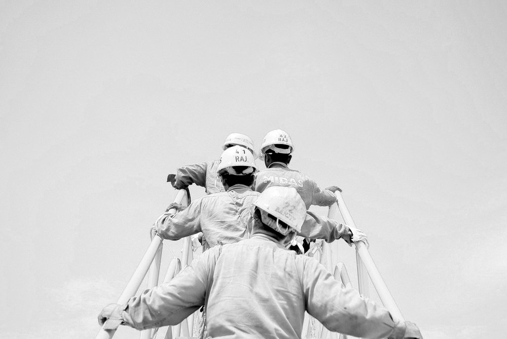 Black and white of group of hard-hat workers climbing stairs